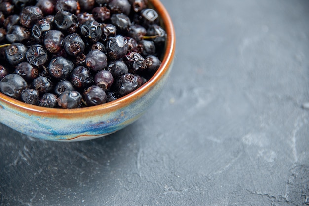 Foto gratuita ribes nero a metà vista inferiore in una ciotola su superficie scura