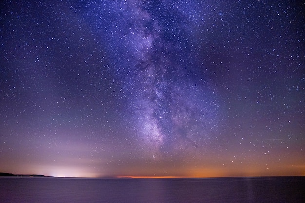 Foto gratuita scatto mozzafiato del mare sotto un cielo scuro e viola pieno di stelle