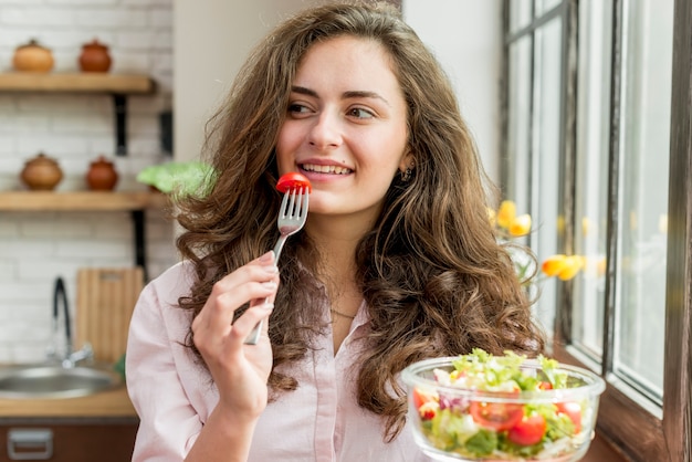 Foto gratuita donna castana che mangia un'insalata