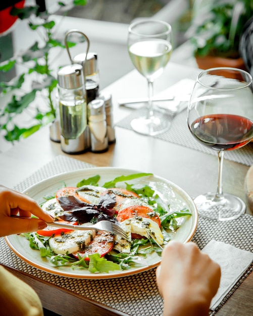 Foto gratuita insalata caprice e un bicchiere di vino rosso