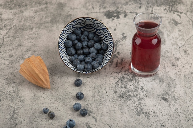 Foto gratuita ciotola in ceramica di deliziosi mirtilli freschi e bicchiere di succo