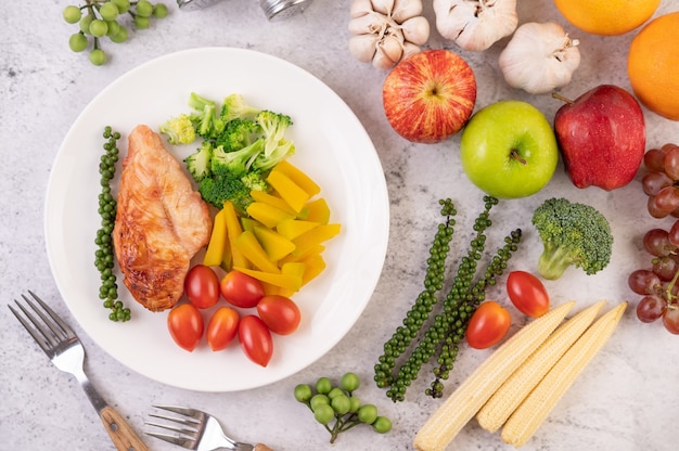 Foto gratuita bistecca di pollo condita con sesamo bianco, piselli, pomodori, broccoli e zucca in un piatto bianco.