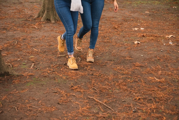 Foto gratuita chiuda in su di due donne in stivali che camminano nel parco