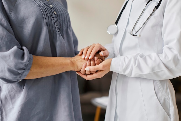 Foto gratuita medico femminile del centro di recupero covid che tiene le mani del paziente più anziano