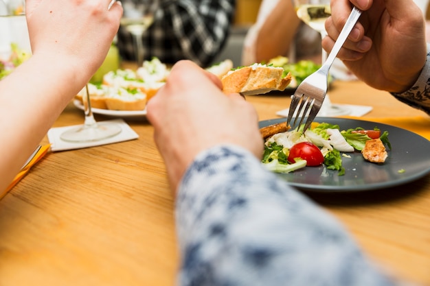 Foto gratuita ritaglia le mani dell'uomo che mangia piatto delizioso