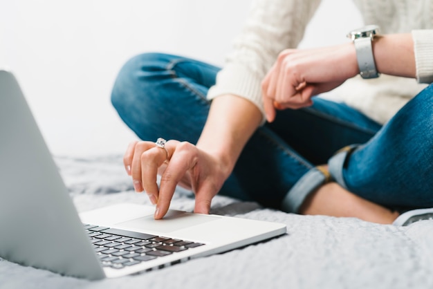 Foto gratuita raccolga la donna che per mezzo del computer portatile sul letto