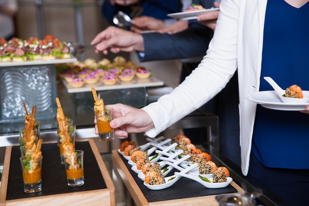 Foto gratuita ritagliata donna prendendo snack dalla tabella a buffet