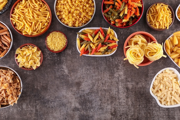 Foto gratuita diversi bambini di pasta in vista dall'alto di piatti con copia spazio sulla superficie grigia