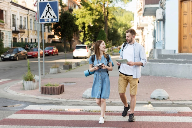 Foto gratuita vista frontale delle coppie turistiche con la mappa e la macchina fotografica sull'attraversamento