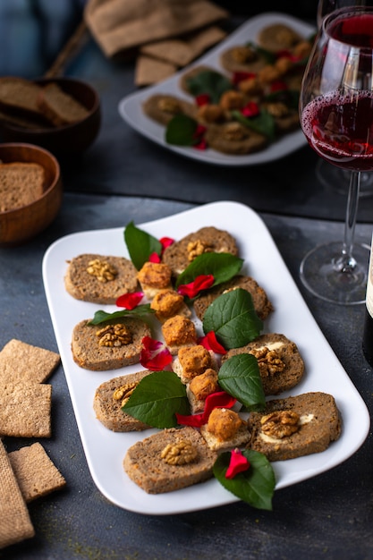 Foto gratuita un patè di verdure di vista frontale con le foglie verdi delle noci insieme ai prodotti del pasto del vino rosso delle patatine fritte sullo scrittorio grigio