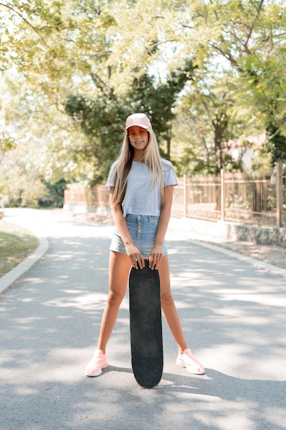 Foto gratuita ragazza del colpo pieno che posa con lo skateboard