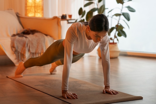 Foto gratuita donna della foto a figura intera che fa yoga a casa