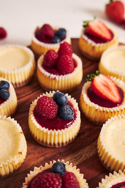 Foto gratuita colpo di alto angolo di cupcakes al formaggio con gelatina di frutta e frutta su un piatto di legno