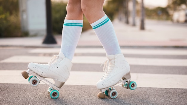 Foto gratuita sezione bassa della donna che indossa il pattino a rotelle d'annata che cammina sulla strada