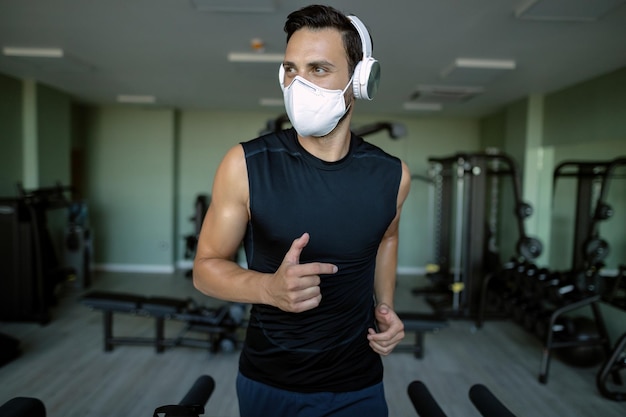 Foto gratuita atleta maschio che indossa una maschera protettiva durante la corsa sul tapis roulant