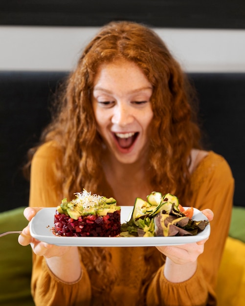 Foto gratuita donna eccitata colpo medio con piatto di cibo