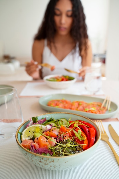 Foto gratuita donna del colpo medio che mangia ciotola di salmone