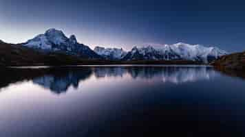 Foto gratuita il monte mont blanc coperto di neve che riflette sull'acqua la sera a chamonix, in francia