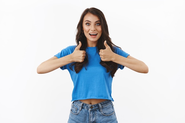 Foto gratuita bella scelta, buon lavoro, stai facendo un ottimo lavoro fidanzata bruna ottimista e solidale in maglietta blu che condivide emozioni positive con la squadra mostra pollice in su in approvazione come gesto sorridente felice