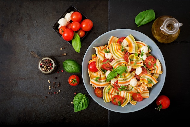 Foto gratuita insalata di farfalle di pasta colorata con pomodori, mozzarella e basilico.