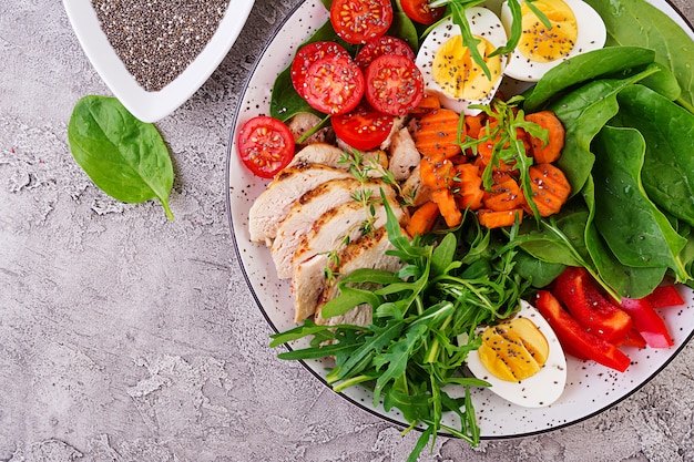 Foto gratuita piastra con un alimento dieta cheto. pomodorini, petto di pollo, uova, carota, insalata con rucola e spinaci. pranzo di keto. vista dall'alto