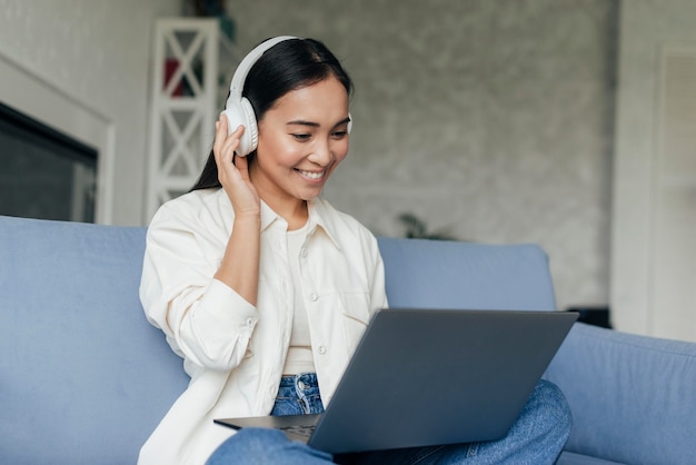 Foto gratuita donna sorridente con le cuffie che lavorano al computer portatile