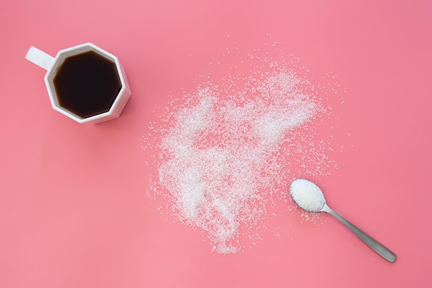 Foto gratuita cucchiaio di zucchero e tazza di caffè su uno sfondo rosa piatto