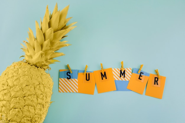 Foto gratuita etichetta estate con molletta vicino l'ananas giallo verniciato su sfondo blu