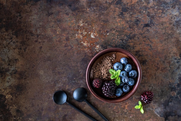 Foto gratuita tre ramekins con mousse di cioccolato con mirtilli mirtilli e menta fresca su uno sfondo di ferro arrugginito