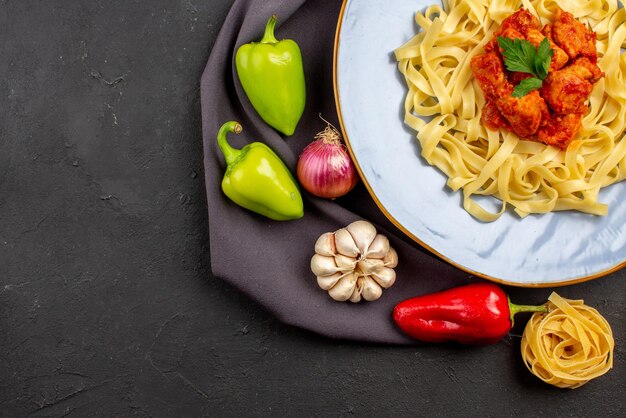 Foto gratuita vista ravvicinata dall'alto pasta pasta palla pepe aglio cipolla accanto alla pasta appetitosa con carne e sugo sulla tovaglia