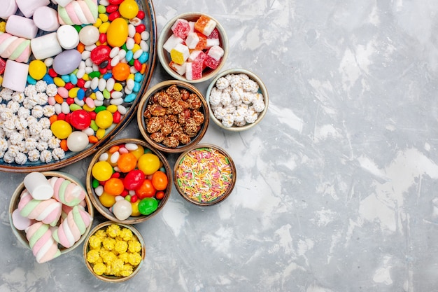 Foto gratuita caramelle dolci e deliziose della composizione nella caramella di vista superiore con la caramella gommosa e molle sulla caramella bianca del goodie dello zucchero della scrivania dolce