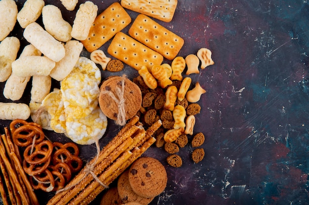 Foto gratuita vista dall'alto copia spazio salato biscotti con pangrattato e grissini su uno sfondo rosa e blu