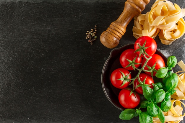 Foto gratuita vista dall'alto della composizione fantastica con basilico, pasta e pomodori