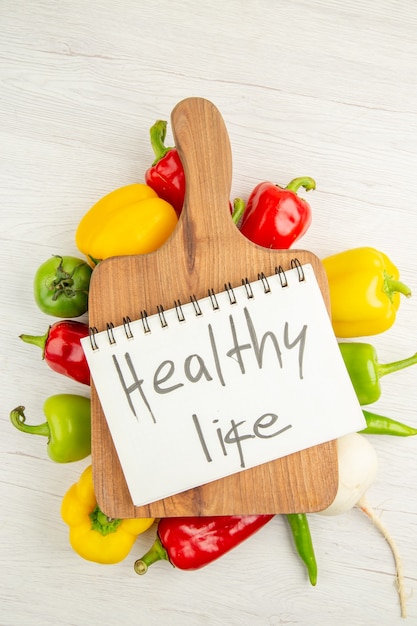 Foto gratuita vista dall'alto peperoni freschi di colore diverso con scrivania in legno marrone su sfondo bianco dieta insalata foto a colori maturi vita sana healthy