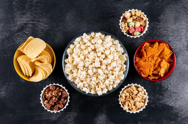 Foto gratuita vista superiore di popcorn e patatine fritte in ciotole su orizzontale nero