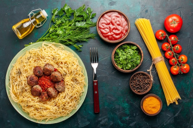 Foto gratuita vista dall'alto gustosa pasta italiana con polpette di carne e condimenti diversi sulla scrivania blu scuro