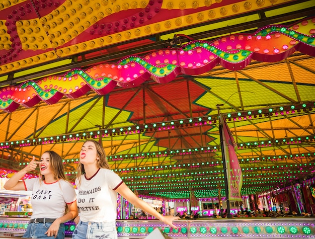 Foto gratuita due amici femminili che stanno al parco di divertimenti