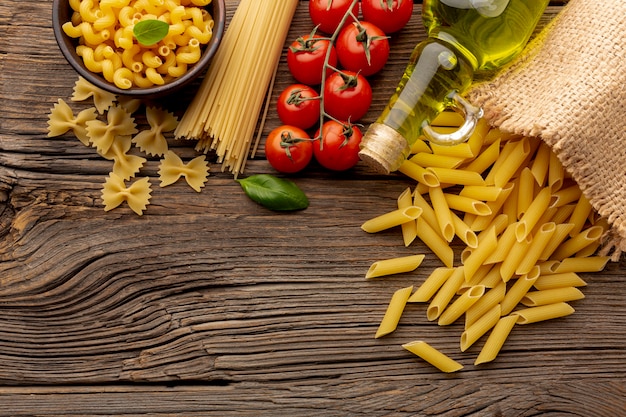 Foto gratuita pomodori ed olio d'oliva crudi del farfalle degli spaghetti del penne sulla tavola di legno con lo spazio della copia