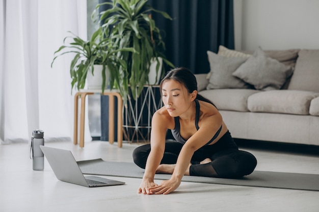 Foto gratuita donna che si allunga sul tappetino da yoga a casa