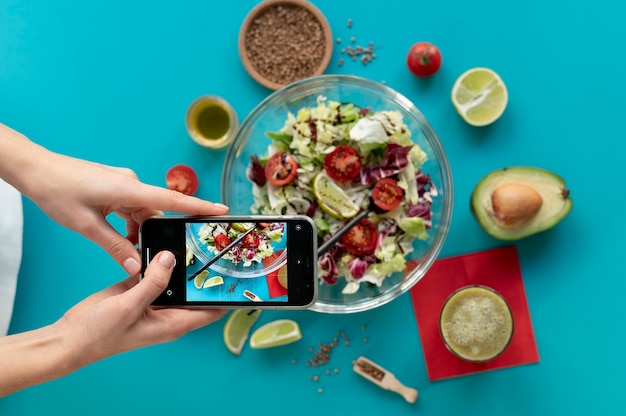 Foto gratuita donna che cattura foto di una ciotola con insalata e una forchetta