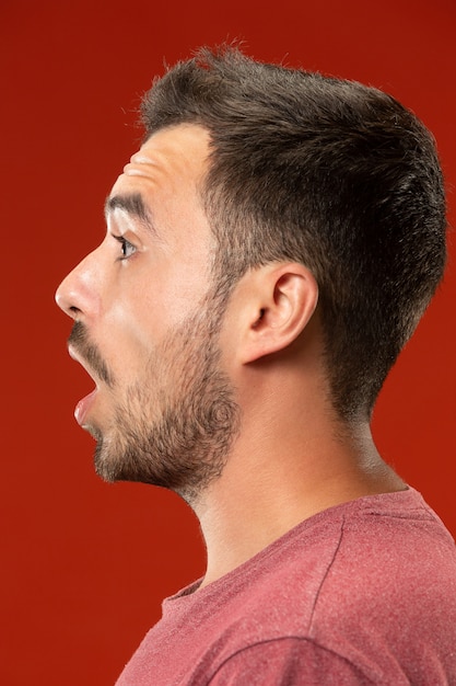 Foto gratuita il giovane uomo attraente che sembra sorpreso isolato su rosso