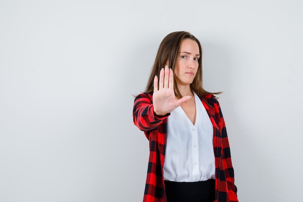 Foto gratuita giovane bella femmina che mostra gesto di arresto in abbigliamento casual e dall'aspetto rigoroso. vista frontale.