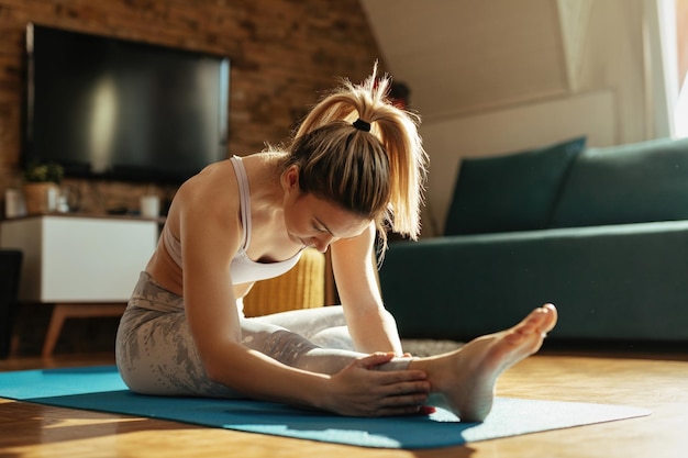 Foto gratuita giovane donna che fa esercizi di stretching sul pavimento a casa