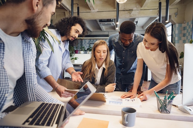 Photo gratuite une équipe de divers collègues dans un bureau moderne discute ensemble de leur projet