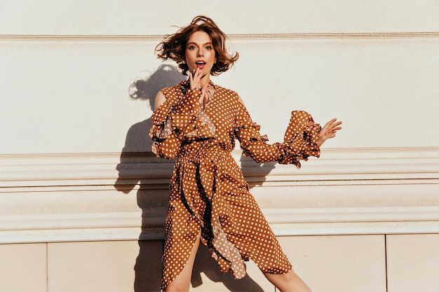 Photo gratuite femme blanche à la mode s'amuser dans la rue modèle féminin caucasien rêveur en tenue marron sautant devant le mur