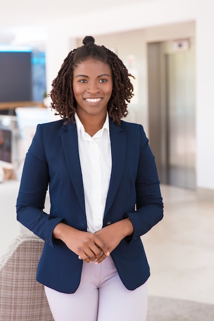 Photo gratuite heureux jeune femme professionnelle posant dans le couloir de bureau