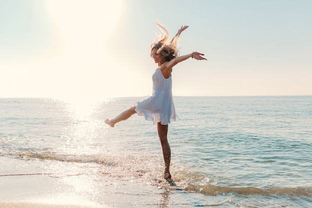 Photo gratuite jeune jolie femme heureuse dansant en tournant autour de la plage de la mer style de mode d'été ensoleillé