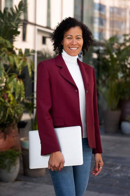 Photo gratuite portrait d'une femme senior en blazer professionnel à l'extérieur et d'un ordinateur portable