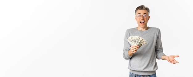 Photo gratuite portrait d'un homme d'âge moyen surpris dans des verres et un pull gris tenant un stand de loterie gagnant de l'argent