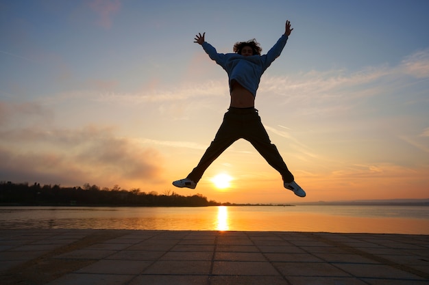 Photo gratuite silhouette d'homme plein coup sautant au coucher du soleil